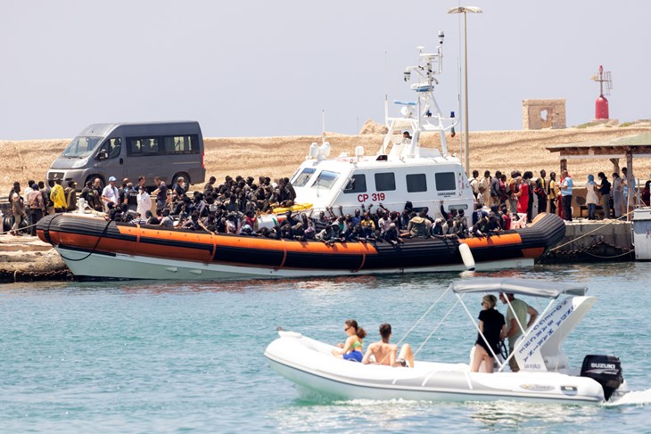 Lampedusa, 28 juni 2023, kl 13:33 Den italienska kustbevakningen sätter i land migranter som räddats på havet utanför Lampedusas kust. Migranterna möts upp av personal från Röda Korset bara ett fåtal meter från de badande turisterna.